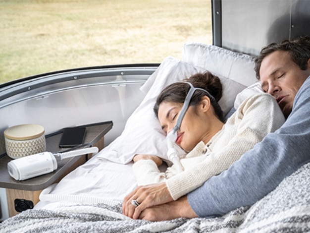  Paar schläft komfortabel auf Reisen mit dem tragbaren Resmed AirMini CPAP-Gerät