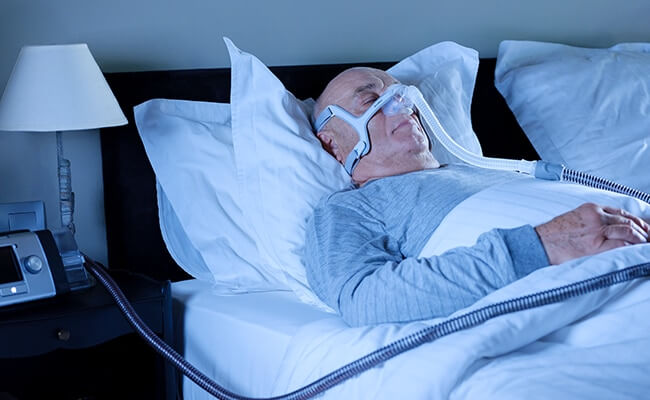 Lumis_COPD_patient_bett_schlafender Mann mit Nasenmaske