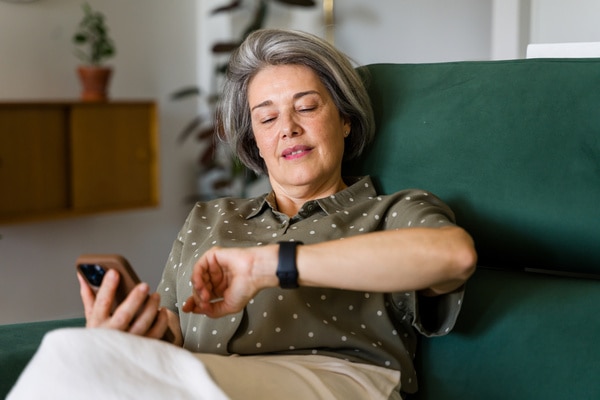  Eine Frau betrachtet ihre Apple Watch und ihr Handy.