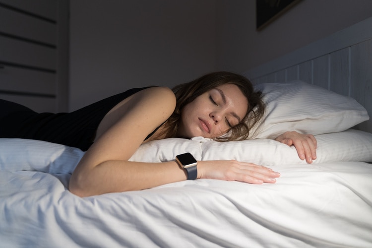 Frau schläft im Bett und trägt eine Apple Watch.